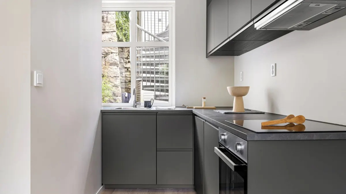 Cocina pequeña con muebles grises y la placa en la encimera