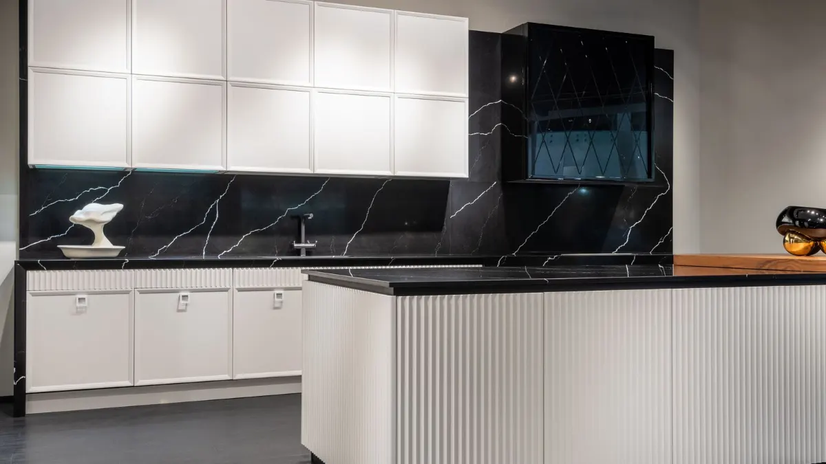 Exposición de cocinas con isla oscura y muebles blancos
