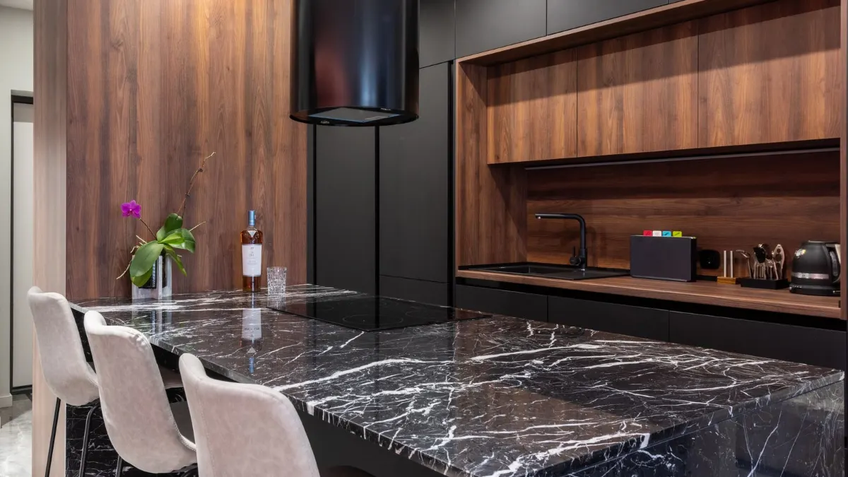 Cocina con isla de mármol oscuro y sin campana sobre la encimera