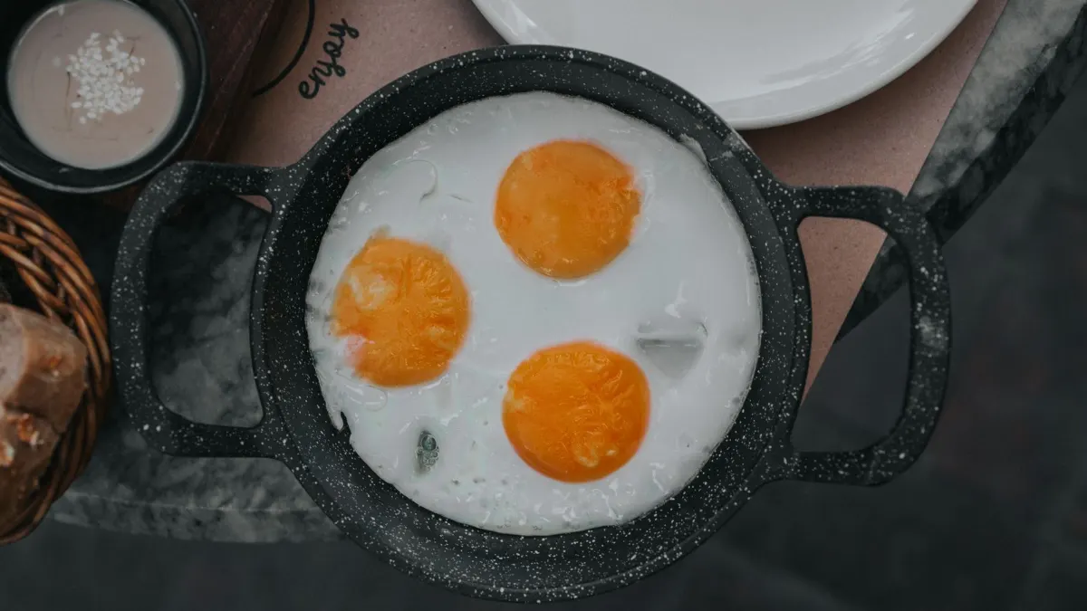 Tres huevos fritos en una sartén antiadherente vista desde arriba
