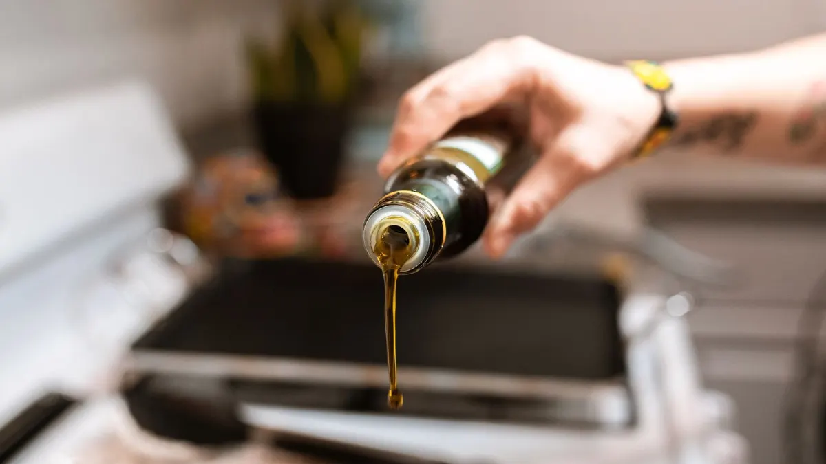 Aceite cayendo en una sartén sobre una placa de cristal negro